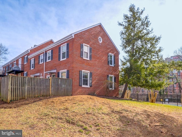 view of side of property featuring brick siding and fence