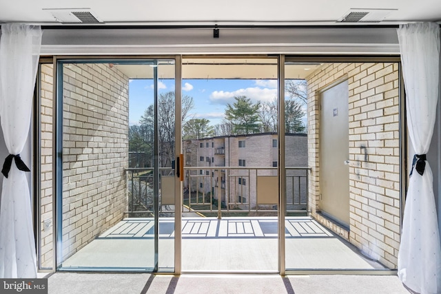 doorway to outside with visible vents and brick wall