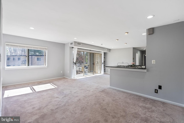 unfurnished living room with recessed lighting, carpet flooring, visible vents, and baseboards