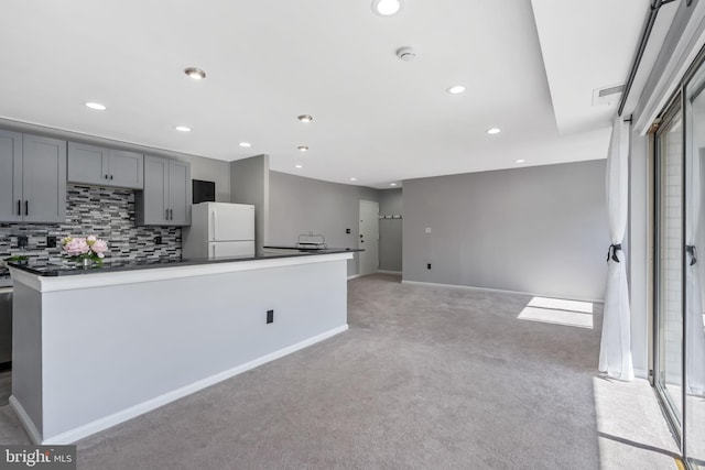 kitchen with visible vents, freestanding refrigerator, gray cabinetry, light carpet, and backsplash