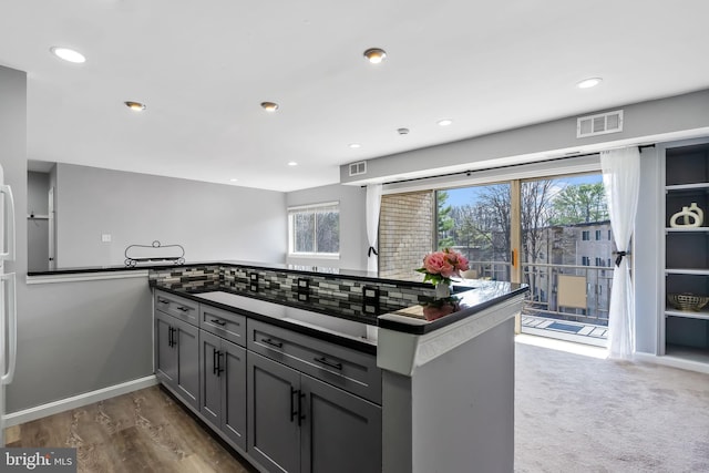 kitchen featuring visible vents, dark countertops, gray cabinetry, and decorative backsplash