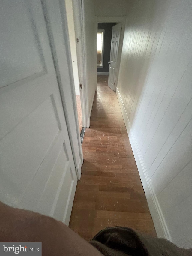 corridor with baseboards and wood finished floors