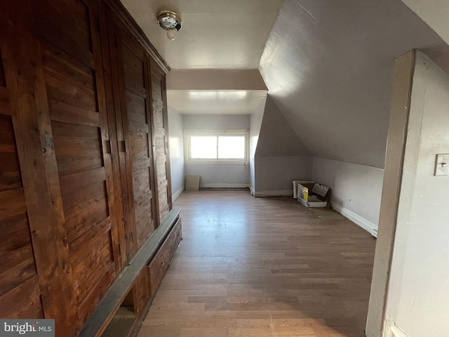 bonus room featuring lofted ceiling, light wood-style flooring, and baseboards