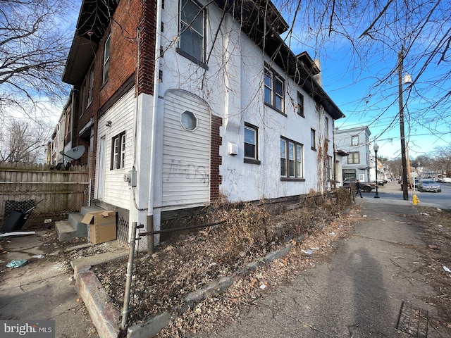 view of home's exterior featuring entry steps, fence, and stucco siding