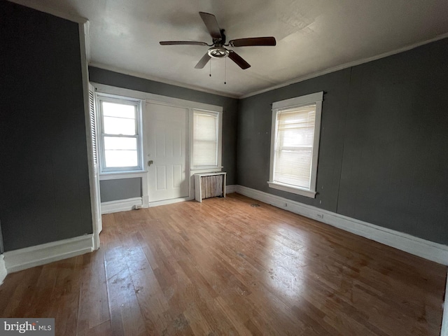 unfurnished bedroom featuring ornamental molding, baseboards, light wood-style floors, and radiator heating unit