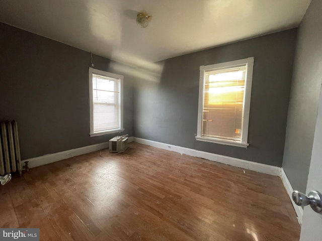 spare room with radiator, baseboards, and wood finished floors