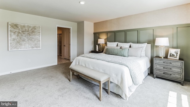 bedroom featuring carpet, baseboards, and a decorative wall