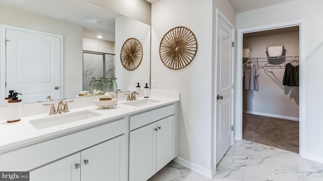 full bathroom with a stall shower, marble finish floor, a sink, and a walk in closet