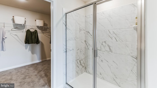 full bathroom featuring a spacious closet, a shower stall, and baseboards