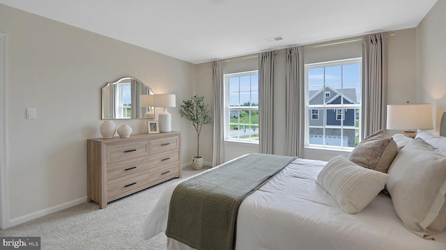 bedroom with light carpet, visible vents, and baseboards