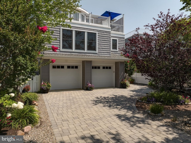 view of front of home with an attached garage, decorative driveway, and fence