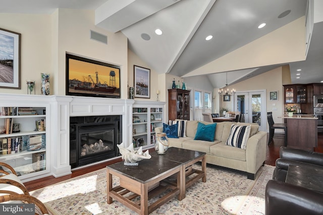 living area with visible vents, an inviting chandelier, wood finished floors, and vaulted ceiling with beams