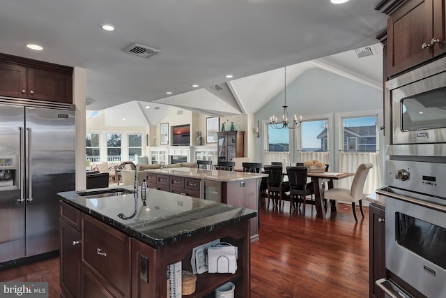 kitchen with visible vents, a center island with sink, an inviting chandelier, a sink, and built in appliances