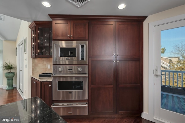 kitchen with visible vents, glass insert cabinets, dark stone counters, stainless steel appliances, and a warming drawer