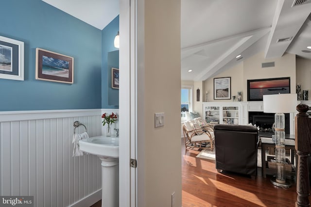 bathroom featuring lofted ceiling with beams, wood finished floors, visible vents, and wainscoting