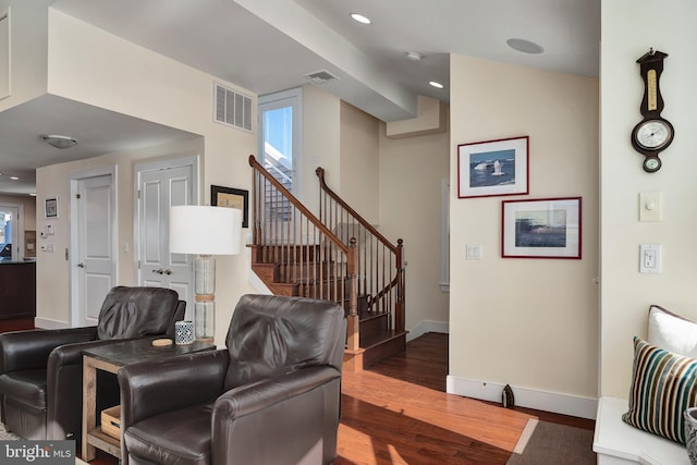 living room with stairway, wood finished floors, visible vents, and baseboards