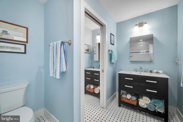 full bathroom featuring baseboards, toilet, and vanity