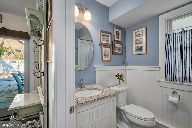 bathroom with wainscoting, toilet, and vanity