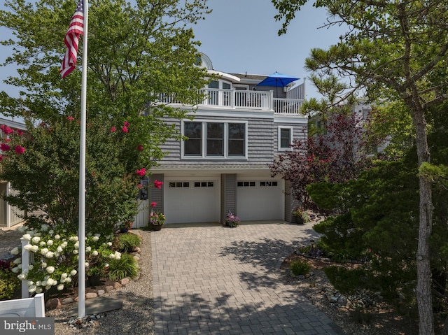 view of front of house with a balcony, decorative driveway, and a garage