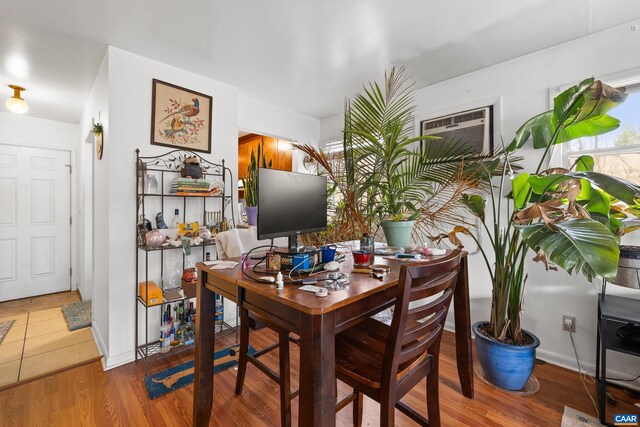 dining space with a wall unit AC, baseboards, and wood finished floors