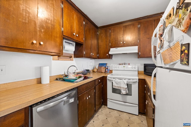 kitchen with under cabinet range hood, white appliances, a sink, light countertops, and light floors