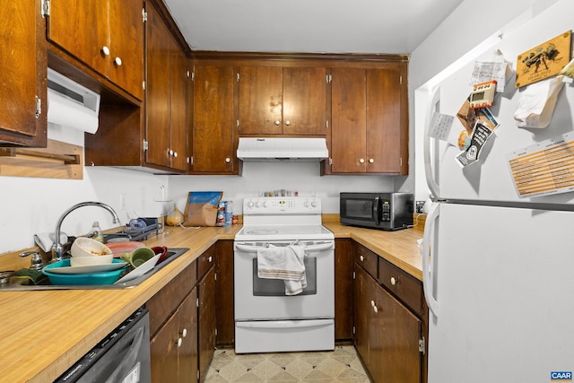 kitchen with under cabinet range hood, white appliances, a sink, light countertops, and light floors