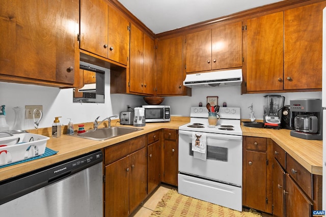 kitchen featuring brown cabinetry, stainless steel appliances, ventilation hood, light countertops, and a sink