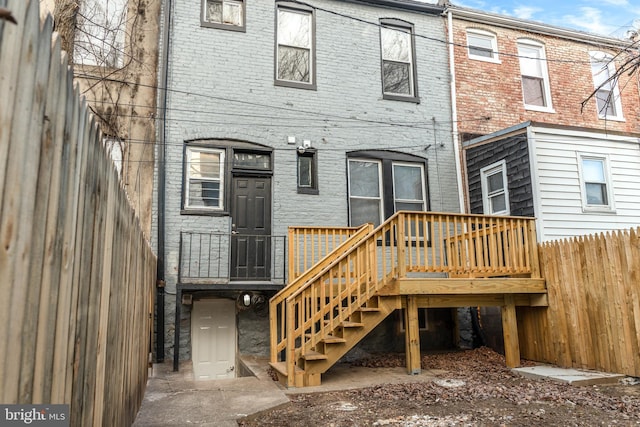 607 N Longwood St, Baltimore, MD 21216 - back of property featuring brick siding, stairway, fence, and a deck