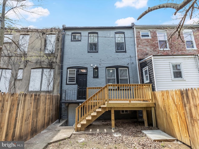 607 N Longwood St, Baltimore, MD 21216 - rear view of property featuring fence, brick siding, stairs, and a deck