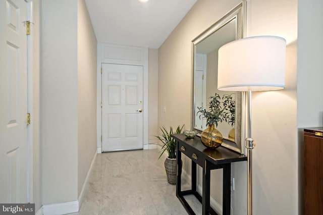 hallway with baseboards and marble finish floor