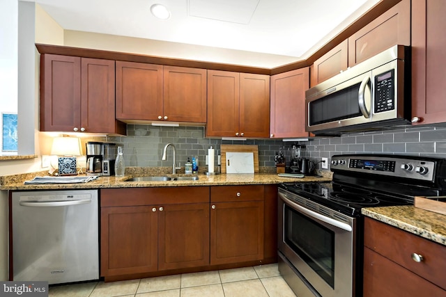 kitchen featuring a sink, stainless steel appliances, light stone counters, and tasteful backsplash