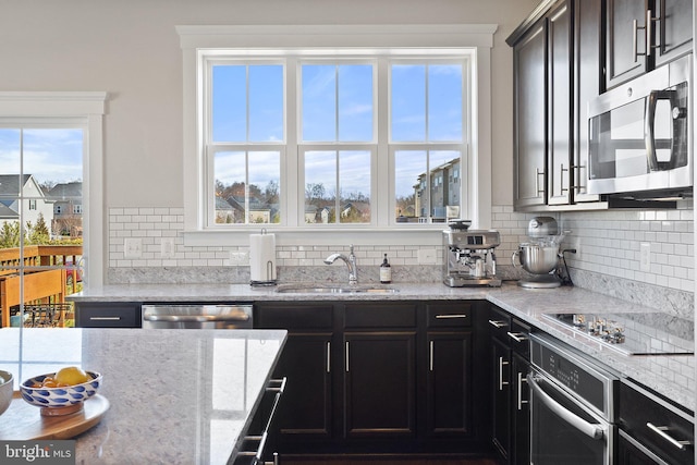 kitchen with a sink, stainless steel appliances, a healthy amount of sunlight, and decorative backsplash