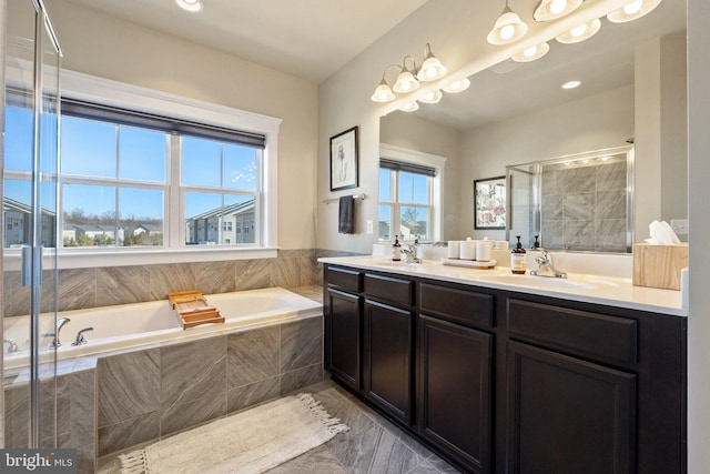 bathroom featuring double vanity, a stall shower, a garden tub, and a sink