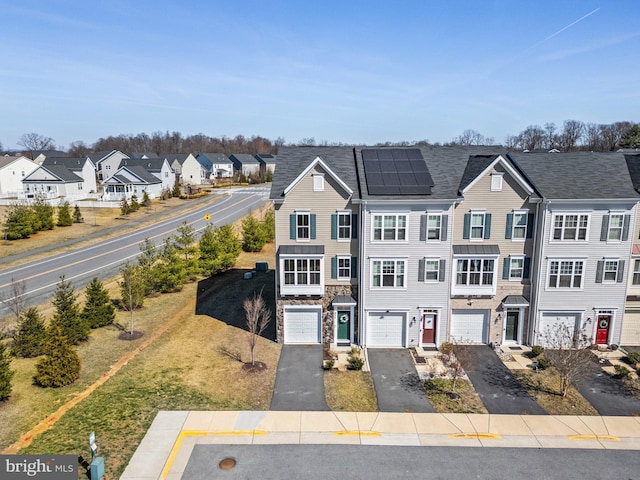 view of property with driveway, stone siding, a residential view, a garage, and solar panels