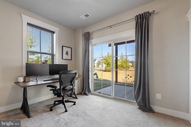 carpeted home office with a healthy amount of sunlight, visible vents, and baseboards