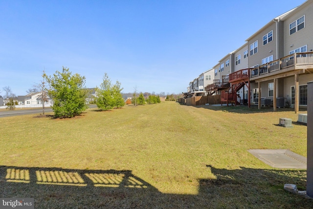 view of yard featuring a deck, stairway, a residential view, and central AC