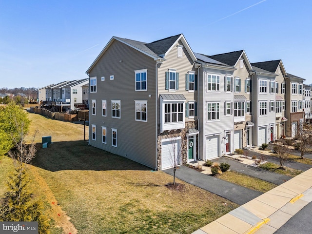 view of front of home with a front lawn, a garage, a residential view, and aphalt driveway