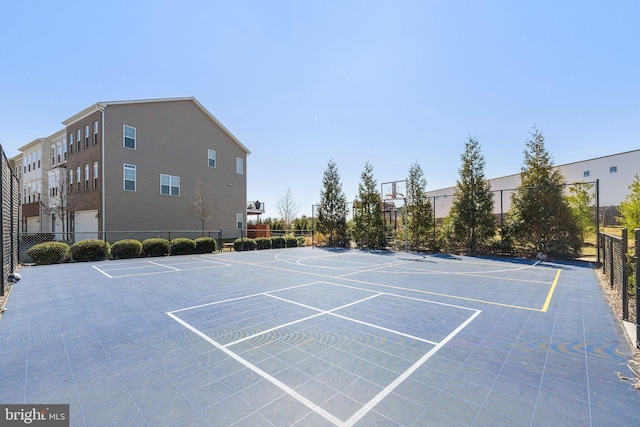 view of vehicle parking with community basketball court and fence