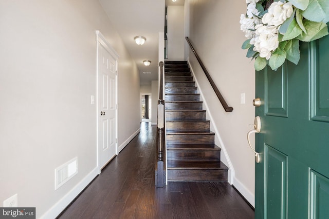 foyer with stairway, baseboards, visible vents, and dark wood-style flooring