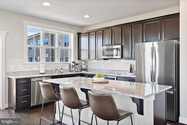 kitchen with a kitchen bar, dark wood-type flooring, appliances with stainless steel finishes, and dark brown cabinetry