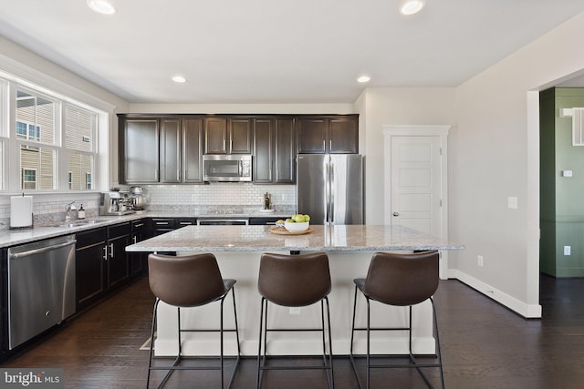 kitchen with stainless steel appliances, a kitchen island, a breakfast bar, and decorative backsplash