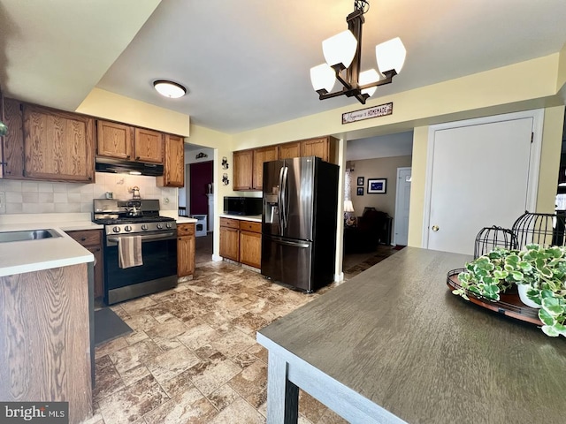 kitchen with under cabinet range hood, appliances with stainless steel finishes, brown cabinetry, and light countertops