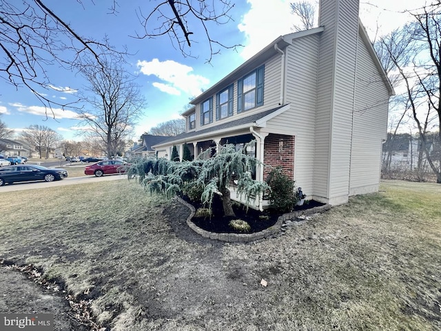 view of home's exterior with brick siding, a chimney, and a lawn