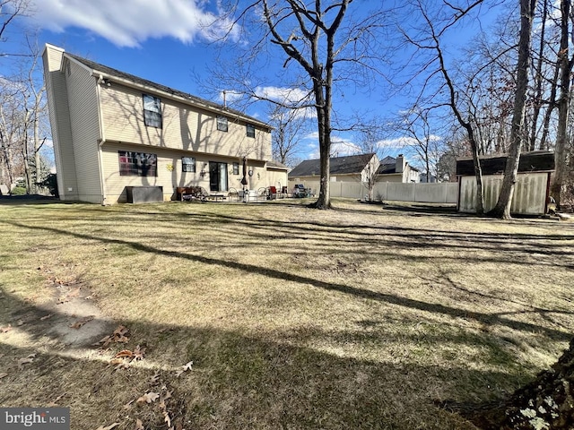 rear view of house with an outdoor structure and fence