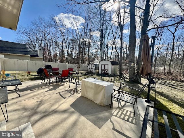 view of patio / terrace featuring a fenced backyard, a storage shed, an outdoor structure, and outdoor dining space