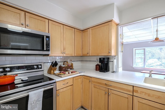 kitchen featuring light brown cabinetry, backsplash, appliances with stainless steel finishes, and a sink