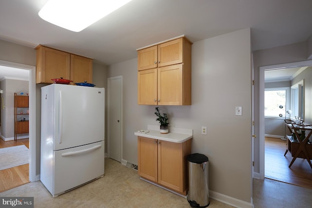 kitchen featuring crown molding, light countertops, freestanding refrigerator, and baseboards