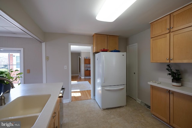 kitchen with light countertops, freestanding refrigerator, baseboards, and a sink