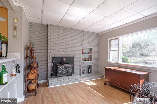 living area with a wood stove, wood finished floors, and a drop ceiling