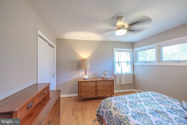 bedroom featuring a ceiling fan, light wood-style floors, baseboards, and a closet